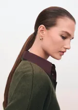 Cardigan de punto medio color verde militar, con cuello en V, cierre frontal con botones y mangas largas de hombros caídos.