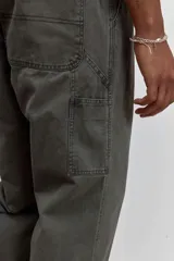 Pantalon de corte recto en color verde oliva, confeccionado en tejido de algodón con acabado ligeramente desgastado, cuenta con bolsillos laterales y cierre frontal.