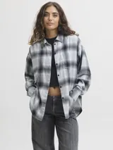 Camisa de franela twill a cuadros en tonos gris, negro y blanco, de calce relajado, con mangas largas, bolsillo en el pecho y cierre frontal de botones.