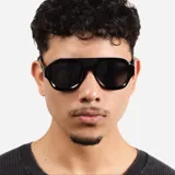 Lentes de sol con marco de acetato negro y diseño de puente plano, estilo aviador moderno con cristales oscuros.