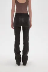 Pantalon de corte flare en color negro, con acabado engomado, tiro medio y cierre frontal con botón y cremallera.
