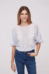 Blusa blanca con rayas verticales celestes, mangas abullonadas y detalles de calado en los hombros y el frente.