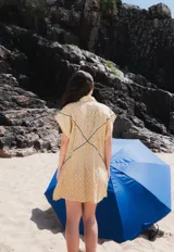 Vestido camisero corto blanco de algodón con bordados negros, cuello camisero, cierre frontal con botones y sin mangas.