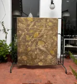 Mantel rectangular grande de algodón con estampado botánico en tonos dorados sobre fondo marrón.