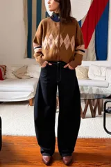 Jean de tiro alto con corte barrel leg, caracterizado por su silueta amplia y redondeada en las piernas. Presenta un diseño de cinco bolsillos y costuras en contraste.