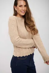 Buzo de tejido de punto color beige, con cuello redondo, manga larga y terminación de ruedo con diseño ondulado.