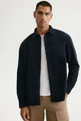 Camisa de pana de algodón suave color negro, con cuello americano, bolsillo superior en el pecho y cierre frontal de botones.