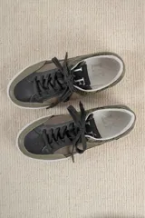 Championes urbanos con diseño de paneles en tonos verde oliva, negro y gris. Presentan una combinación de texturas que incluye cuero liso, gamuza y un panel con estampado de piel de serpiente en el talón. Cuentan con cordones negros y una suela de plataforma blanca con textura acanalada.