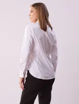 Camisa blanca de algodón con cuello con solapa, abertura central con botones y mangas largas con puño y botón.