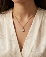 Collar de cadena fina dorada con dije colgante en forma de gota con piedra transparente engastada.
