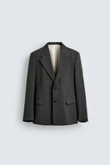 Blazer de corte regular fit en color gris oscuro, confeccionada en tejido con viscosa. Presenta cuello con solapas de muesca, cierre frontal con dos botones, bolsillos laterales con solapa y aberturas en la espalda.