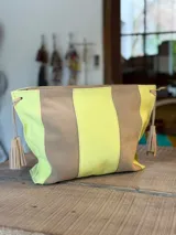 Bandolera de cuero en combinación de colores tostado y verde lima, con diseño a rayas verticales y detalles de borlas colgantes en los laterales.