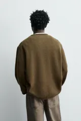 Jersey de punto de lana con corte regular fit, cuello redondo y manga larga. Presenta un diseño minimalista con acabados enrollados en cuello, puños y ruedo.