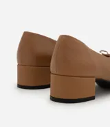 Zapato femenino de cuero color tostado, estilo muñeca con punta redondeada y detalle de mini lazo en la parte superior. Cuenta con tacón bloque de altura mediana.