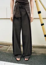 Pantalón de vestir marrón de tiro medio y corte recto, confeccionado en mezcla de algodón y poliéster. Presenta trabillas, cierre con hebilla y un diseño superpuesto en la cintura que aporta un detalle único y sofisticado.