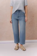 Jean de denim celeste con lavado claro, corte recto y tiro medio-alto, con diseño de cinco bolsillos y cierre frontal con botón y cremallera.