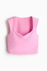 Top deportivo cropped de color rosado con escote corazón y soutien incorporado, confeccionado en tejido funcional con tecnología SculptMove™ y DryMove™.
