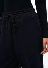 Pantalón de corte recto y holgado, color blanco, con cintura elástica y cordón ajustable. Presenta costuras verticales frontales que estilizan la silueta.