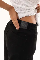 Bermuda de corte amplio y tiro alto en color negro, con cierre frontal de botón y bolsillos laterales.