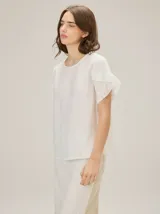 Blusa de lino color rosado, de corte recto y holgado, con cuello redondo y mangas cortas adornadas con volados.