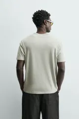 Camiseta de corte relajado (relaxed fit) color blanco roto o crema, con cuello redondo y manga corta.