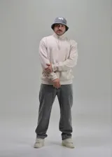 Buzo beige de felpa con cuello alto y cierre frontal parcial, de manga larga y diseño holgado.