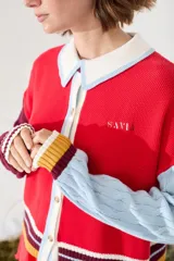 Cardigan de punto con diseño tricolor, de corte relajado, manga larga de tejido trenzado en contraste de color, cuello solapa tipo polo y cierre frontal de botones.