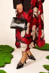 Zapato negro charol con punta fina, tiras finas cruzadas con hebillas doradas y taco kitten heel.