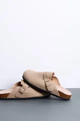 Sandalias cerradas tipo zueco color beige, con tira ajustable y hebilla metálica dorada. Plantilla anatómica y suela de corcho con base de goma.