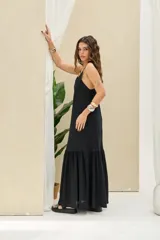 Vestido largo negro de lino con tirantes ajustables con lazo y diseño escalonado con vuelo en la parte inferior.