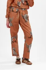 Pantalón largo color marrón con estampado de leopardos alados y constelaciones.