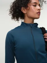 Campera deportiva marrón con cuello alto y cierre frontal completo. Presenta mangas largas con orificio para el pulgar y corte ajustado.