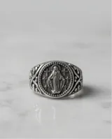 Anillo de plata con acabado empavonado, presenta un diseño circular grabado con la imagen de la Virgen Milagrosa y detalles ornamentales en los laterales.