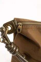 Cartera tipo shopper color marrón, con solapa frontal decorativa en tono más oscuro y tiras con nudos. Incluye herrajes dorados y un charm colgante con cuentas de madera.