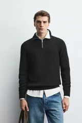 Jersey de punto perlado en color azul marino, con cuello perkins y cierre frontal de cremallera. Presenta manga larga y acabados en rib en puños y bajo.