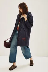 Campera tipo parka de canvas color azul marino, con capucha, cierre frontal y bolsillos laterales. Presenta un bordado en hilo rojo en la parte inferior frontal con la frase 'She's Electric'.