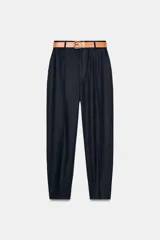 Pantalón tobillero azul marino de tiro medio, con pinzas delanteras, bolsillos frontales, falsos bolsillos con solapa en la espalda y cierre frontal con cremallera, botón y gancho. Incluye cinturón de cuero sintético tostado con hebilla metálica dorada.