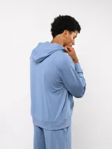 Canguro Umbro de felpa con capucha y cordones ajustables. Presenta el logo de la marca bordado en el pecho en color celeste y bolsillo frontal tipo canguro.