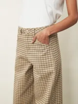 Pantalón tipo jean de corte recto y tiro medio, con estampado de cuadros en tonos beige y marrón. Cuenta con cierre frontal, bolsillos laterales y trabillas para cinturón.