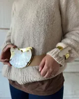 Cinturón de cuero color tostado con hebilla grande irregular de nácar con borde dorado.