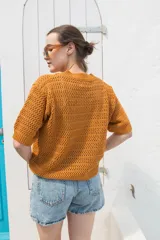 Saco tejido de punto calado con mangas al codo, cuello redondo y cierre frontal con botones de coco. Presenta un diseño versátil y ligero.