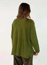 Sweater de punto color verde oliva, con cuello redondo, mangas largas y diseño holgado con costuras visibles en los laterales.