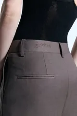 Pantalón sastrero de tiro alto con corte ancho y fluido, confeccionado en mezcla de lana. Presenta detalle de bordado en la cintura, cierre frontal y bolsillos laterales.