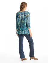 Blusa de calce relajado con estampado geométrico multicolor en tonos azules, verdes y amarillos. Presenta escote redondo con detalle tejido en el contorno, mangas tres cuartos y silueta levemente evasé.