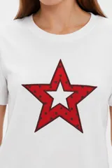 Remera blanca de manga corta y cuello redondo, confeccionada en algodón, con un diseño holgado y estampado frontal de estrella roja con textura y detalles de estrellas pequeñas.