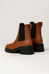 Bota tipo Chelsea de cuero color verde oliva, con paneles laterales elásticos negros y suela track de goma negra con taco cuadrado.
