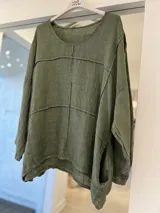 Blusa de lino color verde militar, de corte oversize, cuello redondo y mangas largas, con detalles de costuras visibles y diseño holgado.