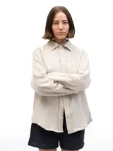 Camisa de lino de manga larga con cuello clásico y cierre frontal de botones. Presenta un corte relajado y un acabado natural.