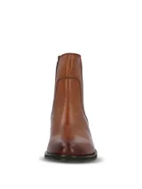 Botín estilo Chelsea color suela, confeccionado en cuero con paneles elásticos laterales en color marrón oscuro. Presenta punta redonda, taco cuadrado bajo y suela de goma.