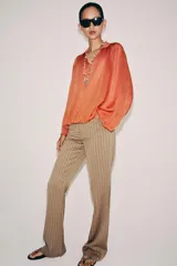 Top de punto color naranja con cuello polo, escote en V y mangas largas amplias con bajo abullonado.
